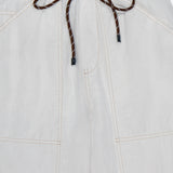 Close-up of the Atlas Drawcord Linen Pant by RAG & BONE: a high-rise white pant with visible stitching, black-tipped drawstring waist tied in a bow, lightweight fabric, and large front pockets.