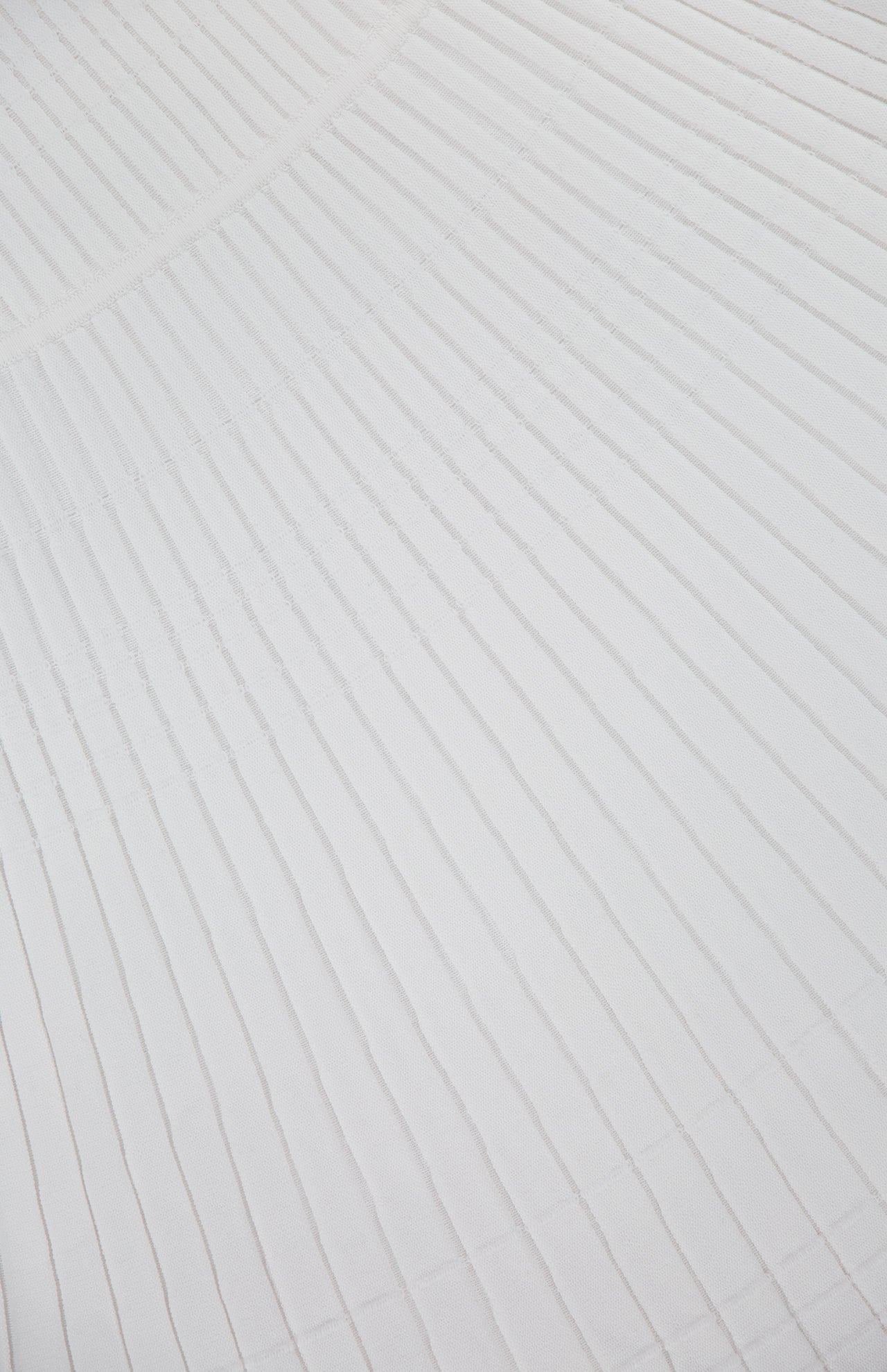 Close-up of the RAG & BONE Ayan Mini Dress with Fringe Trim, showcasing its white fabric detailed with evenly spaced, radiating lines that form a subtle fan-like pattern.