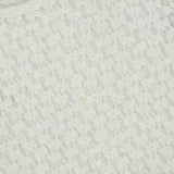 Close-up of a Rag & Bone Bardot Long Sleeve Top in off-white, featuring a fitted, semi-sheer silhouette with an intricate, repeating diamond lace pattern.