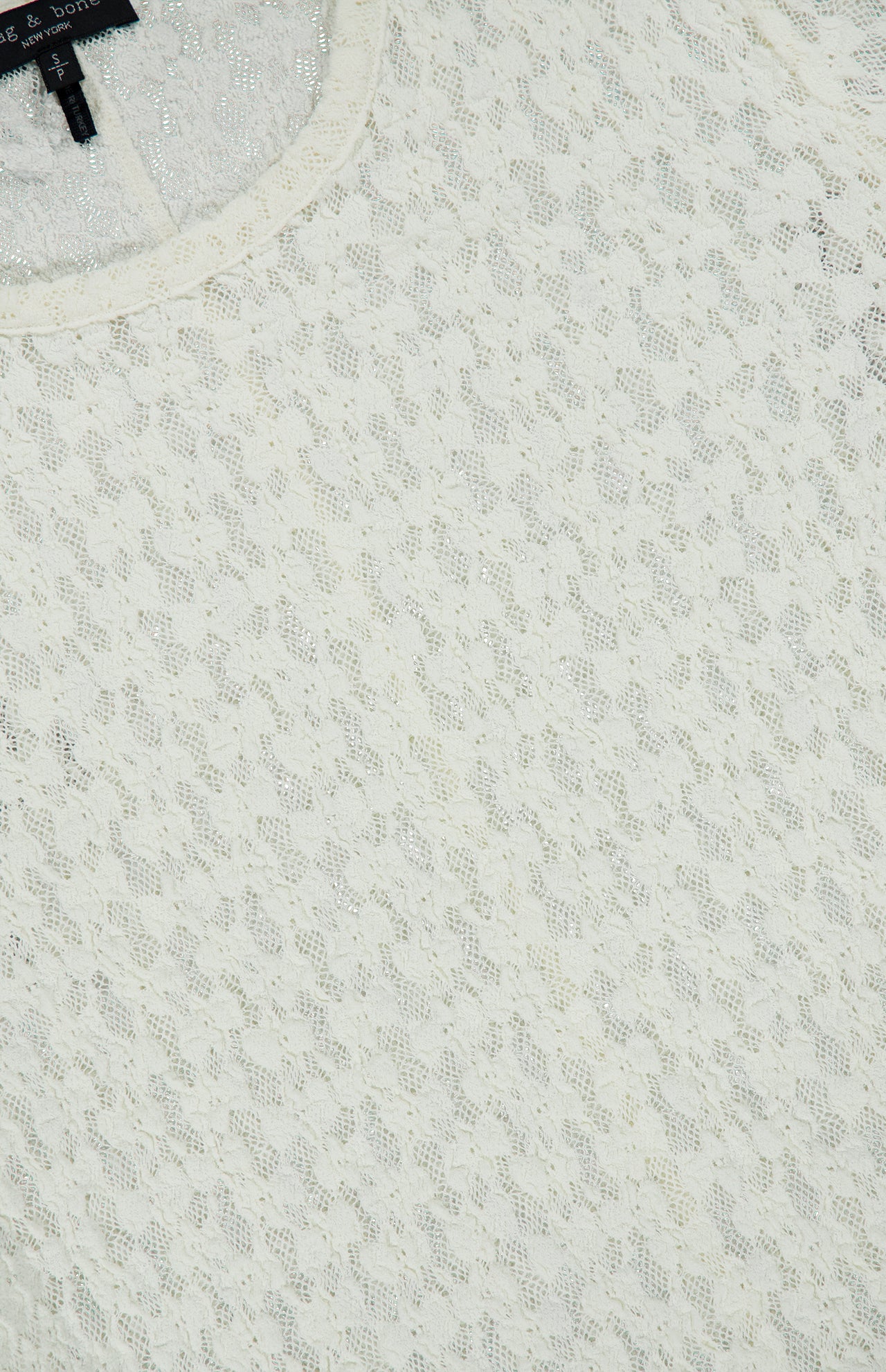 Close-up of a Rag & Bone Bardot Long Sleeve Top in off-white, featuring a fitted, semi-sheer silhouette with an intricate, repeating diamond lace pattern.