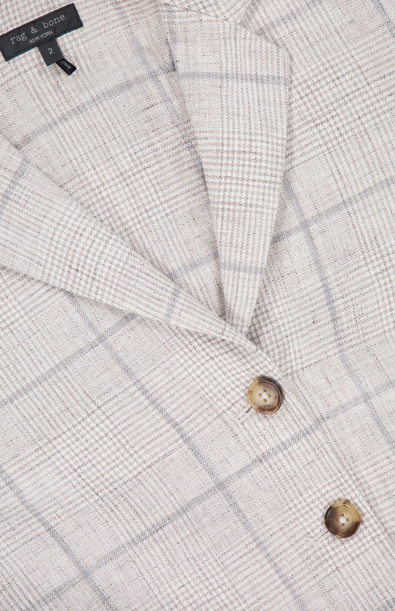 Close-up of the Chappell Plaid Linen Blazer by RAG & BONE, featuring a beige plaid pattern with thin grey lines, two brown buttons, and a visible black size tag labeled 2 near the collar for versatile style.