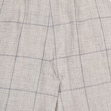 Close-up of the RAG & BONE Chappell Plaid Linen Pant in beige with a subtle blue and gray plaid, highlighting the waistband, upper leg, and fine fabric texture.