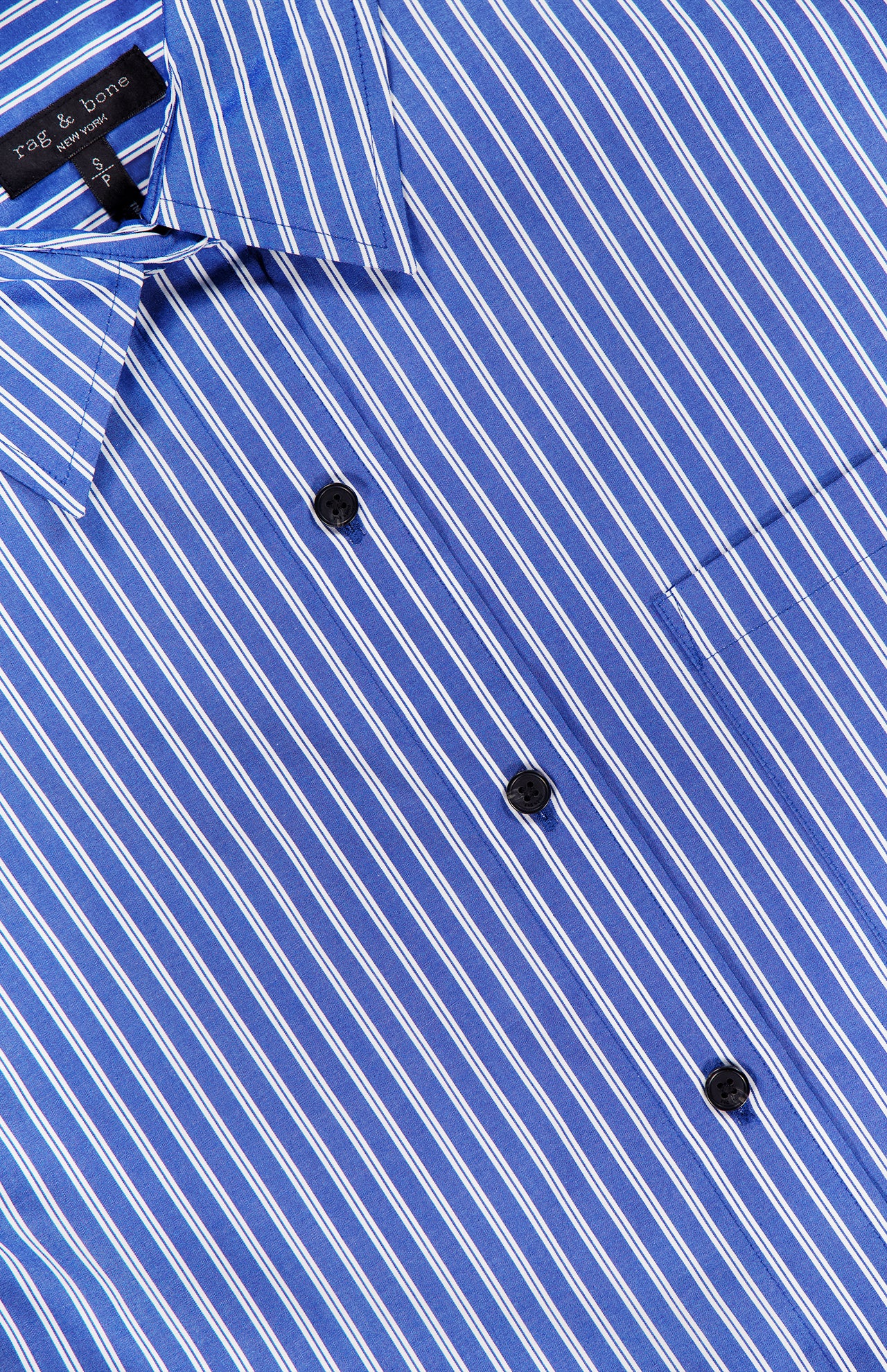 A close-up of the Connie Short Sleeve Stripe Shirt by RAG & BONE, featuring blue fabric with white vertical stripes, black buttons, a chest pocket, and a visible collar and brand label—a modern wardrobe staple.