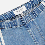 Close-up of the Featherweight Logan Track Pant in Eversport by RAG & BONE, featuring blue featherweight denim, elastic waistband, white side stripes, and a visible brand label. These relaxed track pants provide effortless style and comfort.