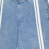 A close-up of light blue Featherweight Logan Track Pant in Eversport by RAG & BONE. These wide-leg pants feature an elastic waistband, vertical white side stripes, relaxed fit, visible stitching, and a signature brand label.