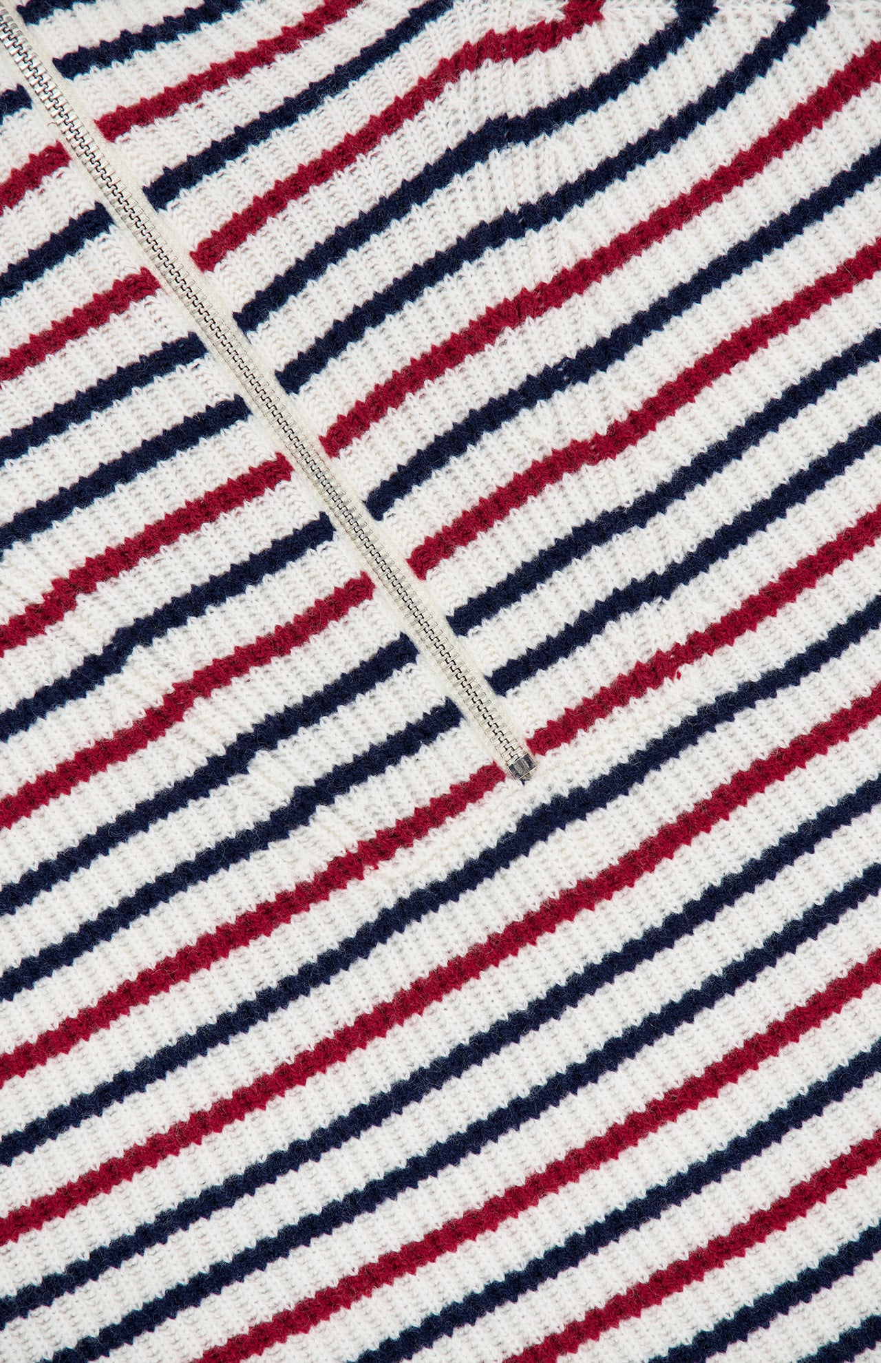Close-up of the Georgie Stripe Half Zip Sweater by RAG & BONE, showcasing ribbed fabric with horizontal red, navy blue, and white stripes and a white zip neck running diagonally across the upper left.