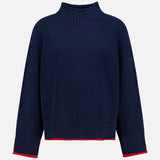The Hazel Roll Neck Sweater by RAG & BONE is a navy blue, long-sleeve cotton-blend sweater with a high ribbed collar, ribbed cuffs, and hem. This mock neck style features thin red trim on the cuffs and hem and is displayed against a plain white background.