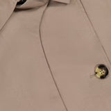 Close-up of the RAG & BONE Jamie Cropped Trench Coat, featuring its collar, partially visible black label, buttonhole, and a single brown button sewn with tan thread—a timeless spring jacket.