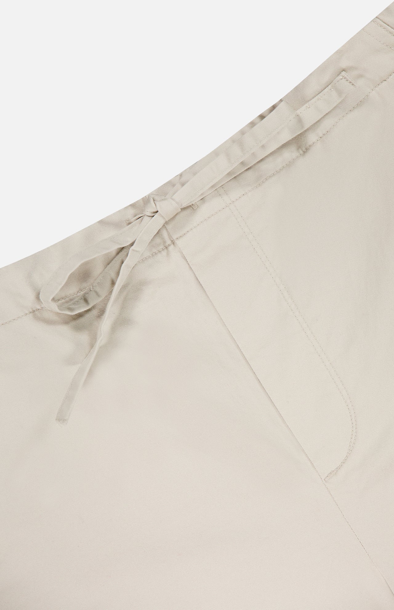 Close-up of RAG & BONE's Jolie Wide Leg Carpenter Pant in light beige, showcasing a drawstring waist, visible stitching, smooth fabric, and relaxed-fit carpenter style.