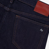 Close-up of the RAG & BONE Kinsley Low Rise Full Bootcut Jean in Dark Rinse, featuring vintage stretch denim, a back pocket with brown stitching, a small white embroidered logo, and a brown leather patch on the waistband.