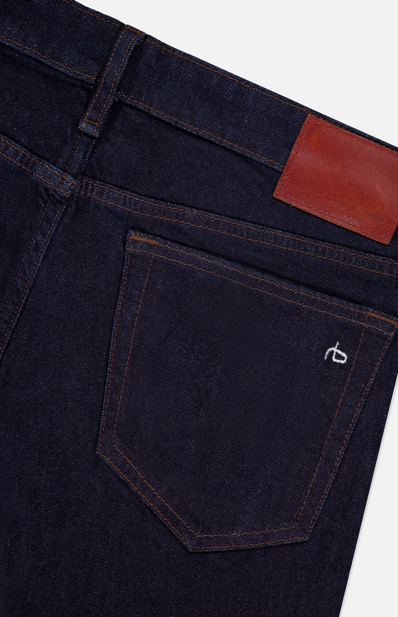Close-up of the RAG & BONE Kinsley Low Rise Full Bootcut Jean in Dark Rinse, featuring vintage stretch denim, a back pocket with brown stitching, a small white embroidered logo, and a brown leather patch on the waistband.