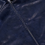Close-up of the Krista Faux Leather Jacket by RAG & BONE, highlighting the shiny navy blue faux leather texture, a partially unzipped silver zipper, a pointed collar, and part of the front pocket—showcasing the sleek appeal of this modern cropped bomber style.