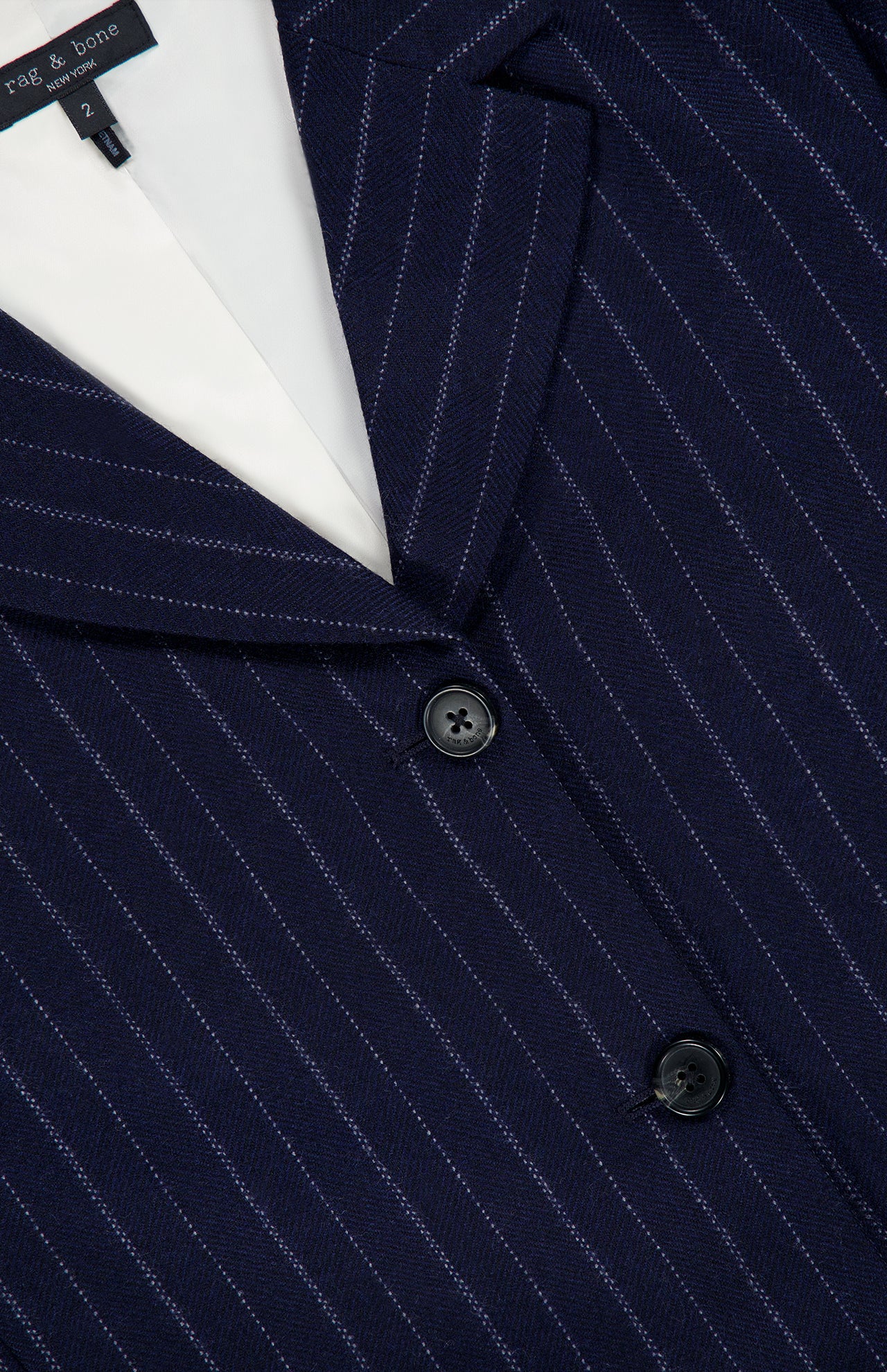 Close-up of the RAG & BONE Lawrence Striped Crop Blazer in pinstripe navy, featuring two black buttons and white lining—perfect for modern women’s suiting.
