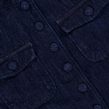 Close-up of the RAG & BONE Mercer Pocketed Denim Blazer in dark blue, showcasing its slim fit design with four flap pockets, round buttons, and visible stitching. A small branded clothing tag is partially visible at the neckline.