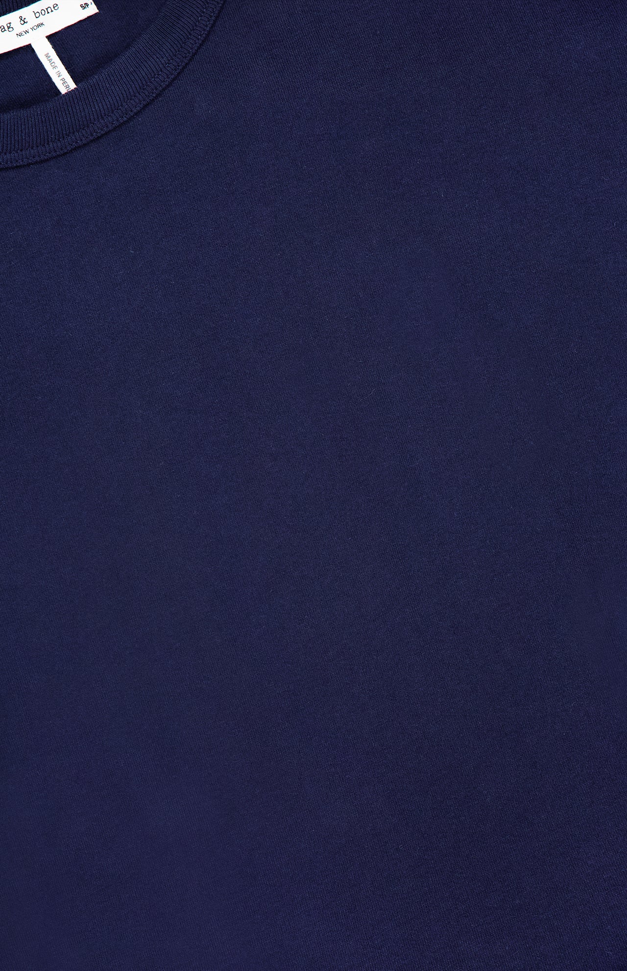 Close-up of the Mica Tie Tee Dress by RAG & BONE in navy blue, featuring a crew neckline. A hint of the white collar tag with black text is visible.