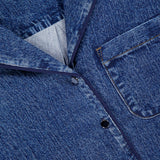 Close-up of the Miramar Slink Short Sleeve Lounge Shirt by RAG & BONE in blue denim-look drapey fabric, featuring a chest pocket, classic collar, contrast stitching, dark buttons, and a visible brand label on the collar.