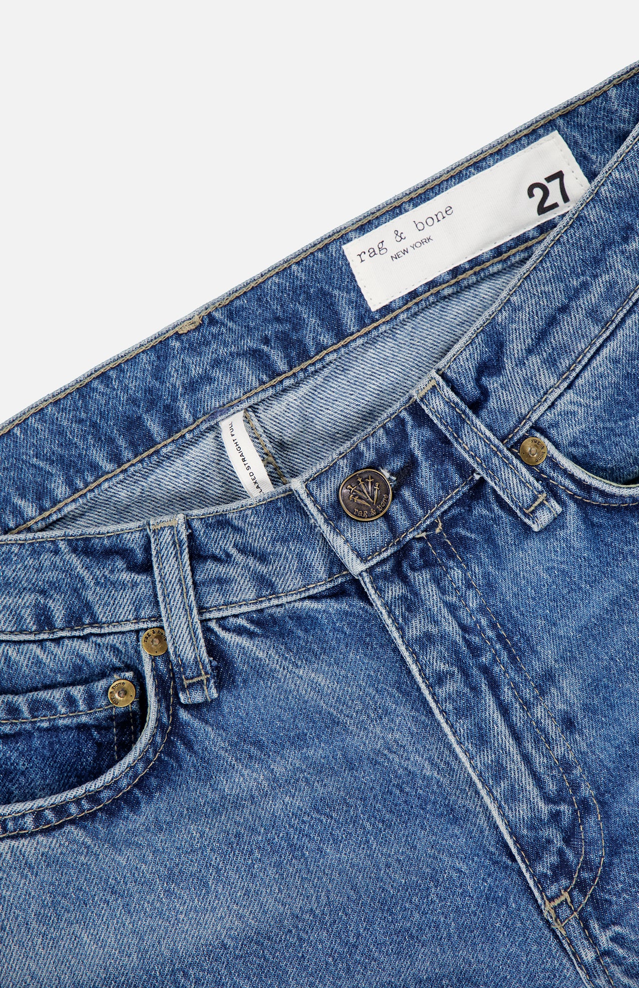 Close-up of the RAG & BONE Saige Full Straight Boxer Jean in Echo, featuring front pockets, button closure, visible stitching, and a white label inside the waistband with branding and size 27.