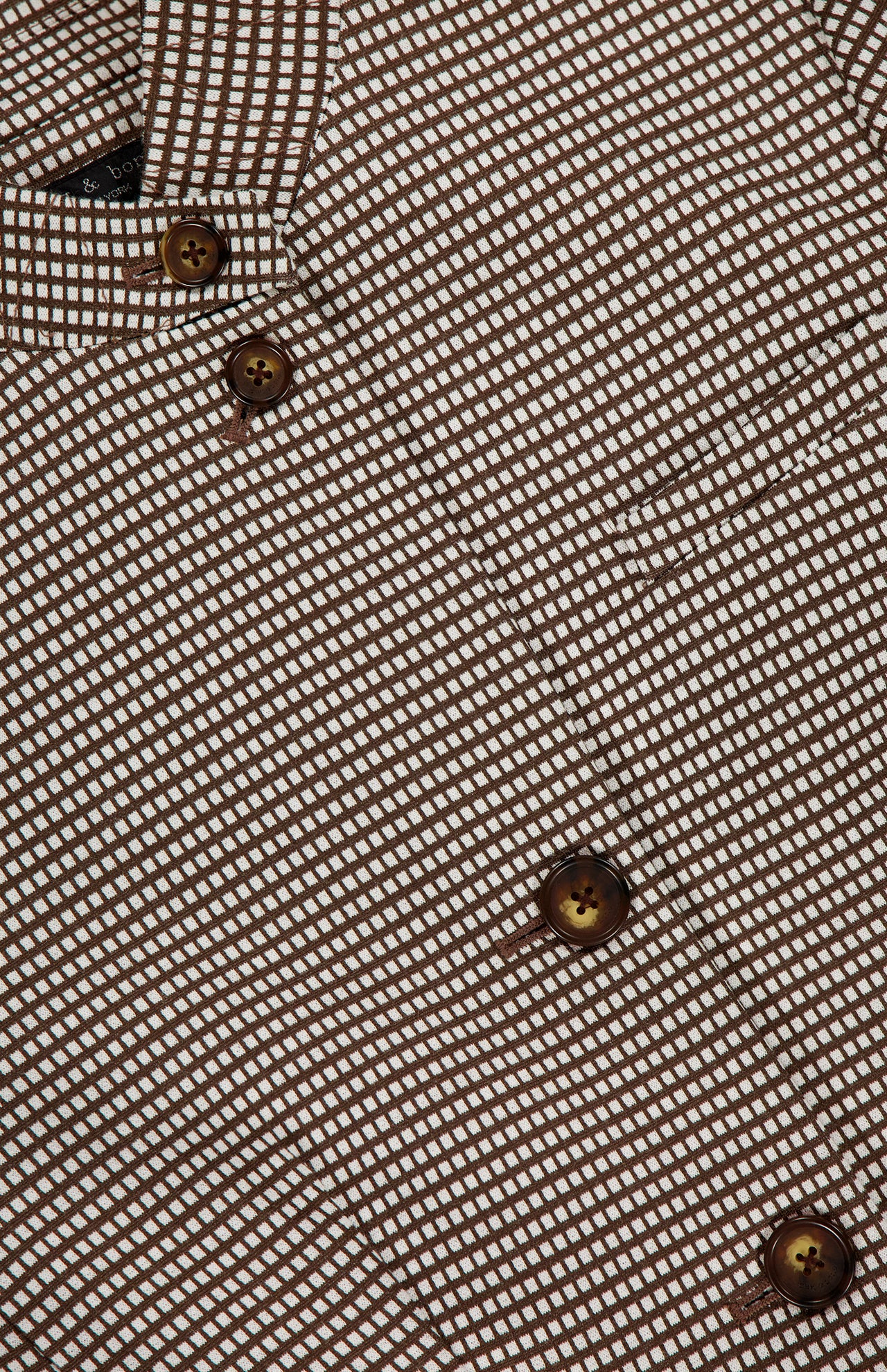 Close-up of the RAG & BONE Slade Printed Blazer, featuring a brown and white micro check print, four dark brown buttons, and a visible right-side pocket.