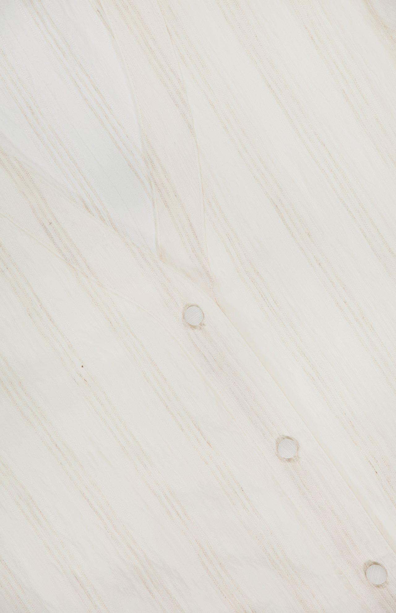 Close-up of the RAG & BONE Taylor Short Puff Sleeve Shirt, an off-white top featuring semi-transparent cream fabric with diagonal beige stripes and three small metal grommets on the surface.