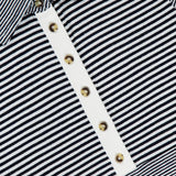 Close-up of The Knit Button Stripe Polo T-shirt by RAG & BONE, a black and white knit polo with gold buttons, button-front placket, and chic striped design. Brand label reads RAG & BONE.