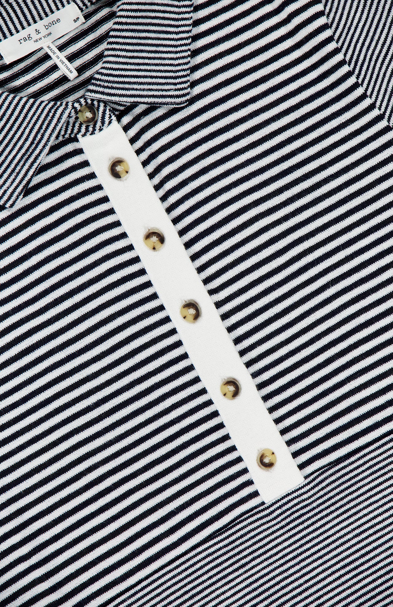 Close-up of The Knit Button Stripe Polo T-shirt by RAG & BONE, a black and white knit polo with gold buttons, button-front placket, and chic striped design. Brand label reads RAG & BONE.