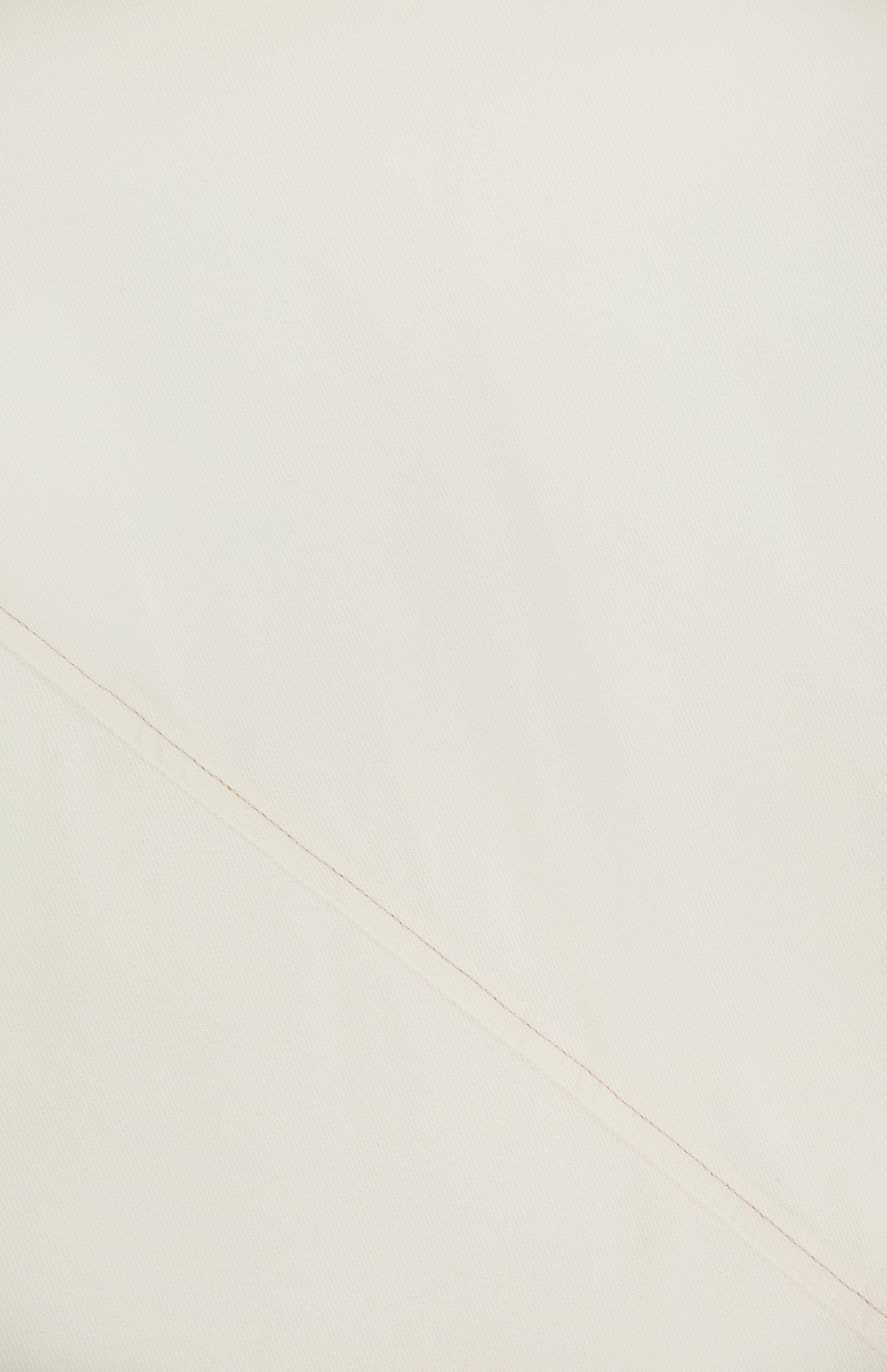 A close-up of soft light beige fabric with a subtle diagonal seam highlights the fine weave and texture—ideal details in the Ultra Featherweight Lisbon Dress by RAG & BONE.