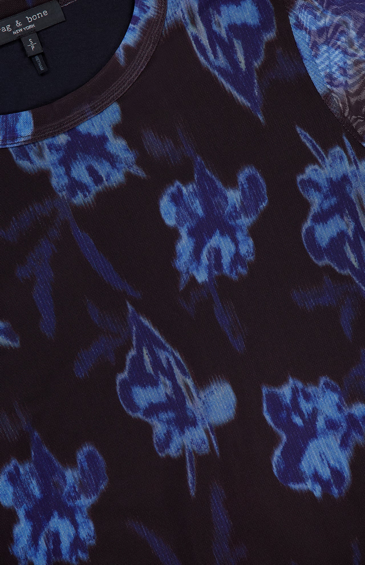 A close-up of the RAG & BONE Yana Printed Mesh Long Sleeve T-shirt, a black stretch mesh top with a blue and purple abstract floral pattern and a partially visible neckline tag.