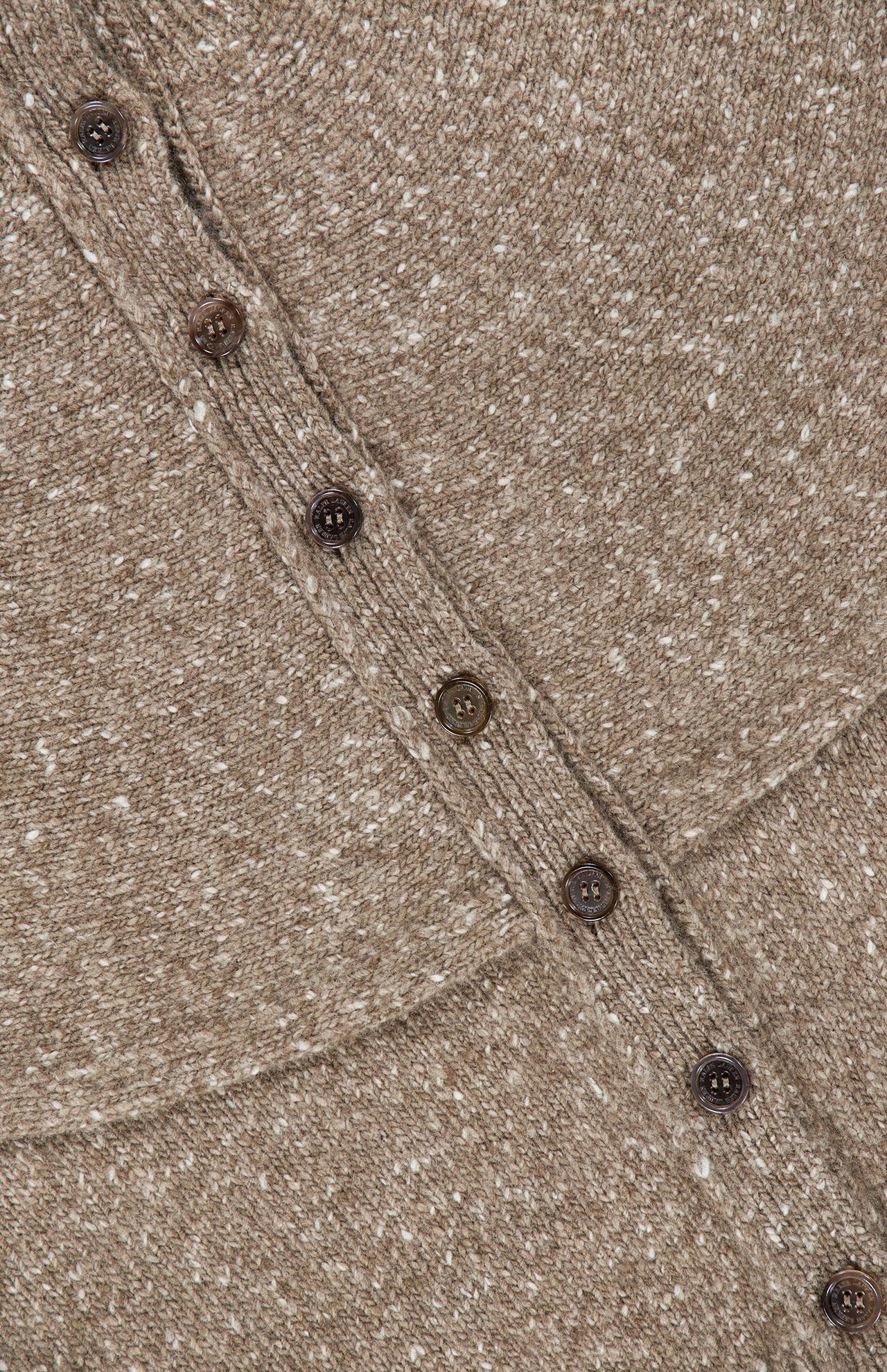 Close-up of the RALPH LAUREN COLLECTION Cashmere Turtleneck Cardigan Sweater in beige, highlighting its speckled knit texture, diagonal row of brown buttons, and visible stitching on the fabric.
