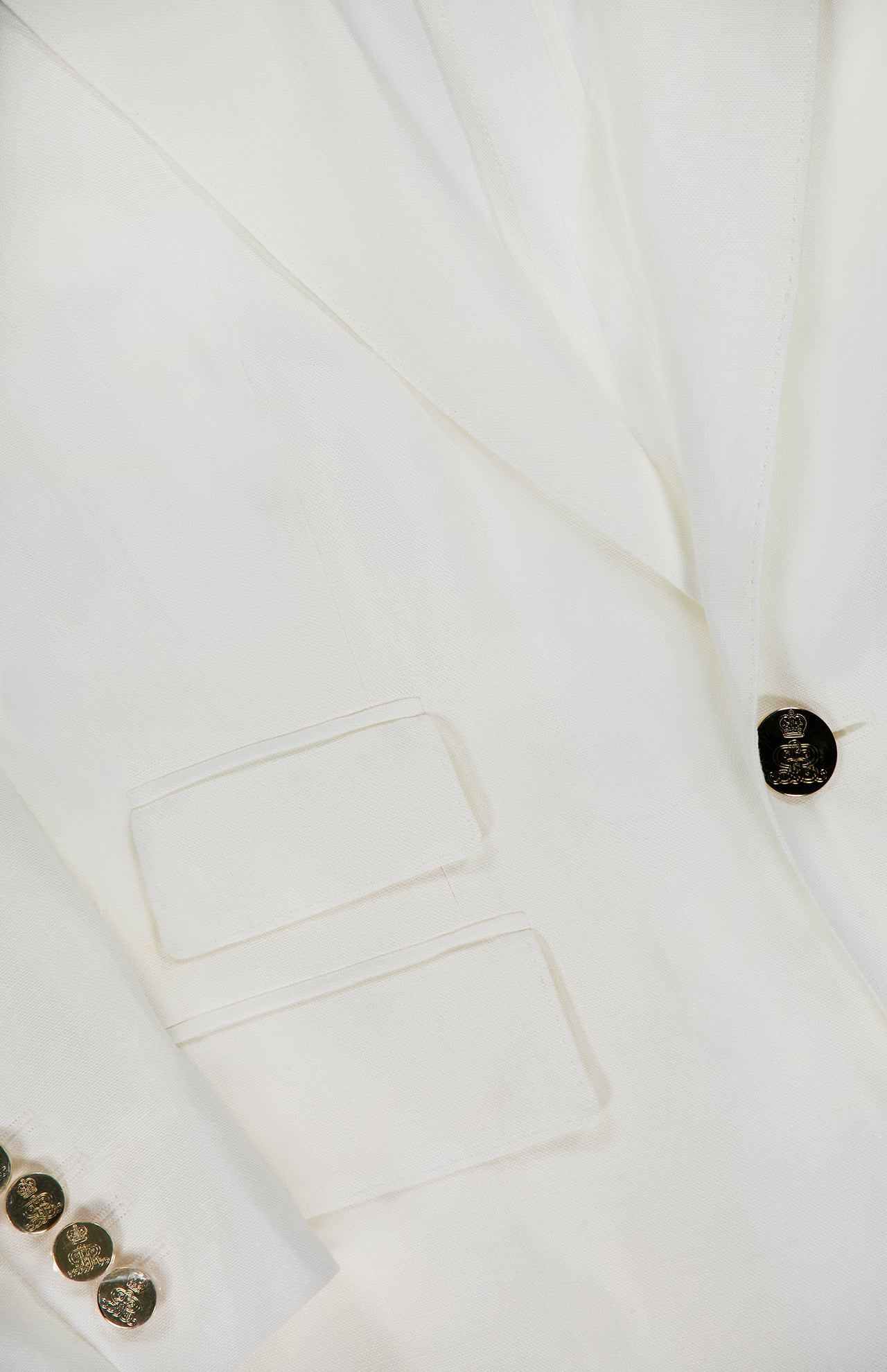 Close-up of the RALPH LAUREN COLLECTION Classic Linen Parker Blazer, featuring an off-white hue, two front pockets, a single black button closure, and four metallic sleeve buttons. Smooth fabric and modern slim fit tailoring.