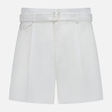 The Denise Classic Linen Shorts by RALPH LAUREN COLLECTION are high-waisted cream shorts with a matching belt and front pleats, ideal for summer suiting and shown against a plain white background.