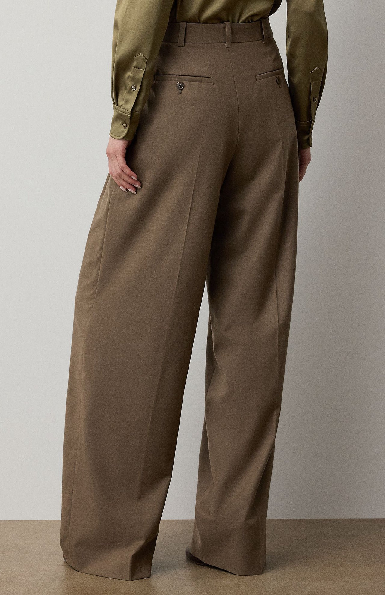 Back view of RALPH LAUREN COLLECTION Fine Wool Standard Pants in olive-brown, featuring a relaxed fit, stretch-wool fabric, a high waist, belt loops, and buttoned back pockets.