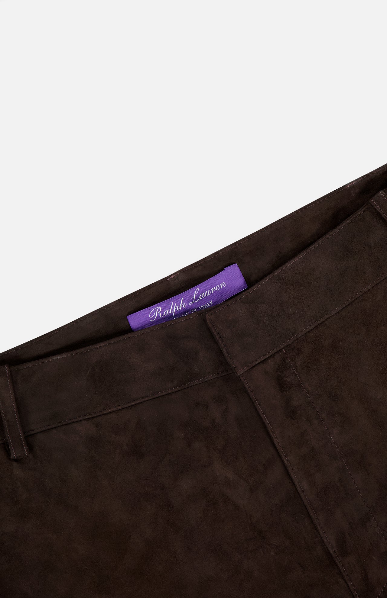 Close-up of the waistband on Keegan Suede Full Length Pant by RALPH LAUREN COLLECTION in dark brown lamb suede, mid-rise with straight leg. Features a visible purple label inside. Made in Italy, shown against a plain white background.