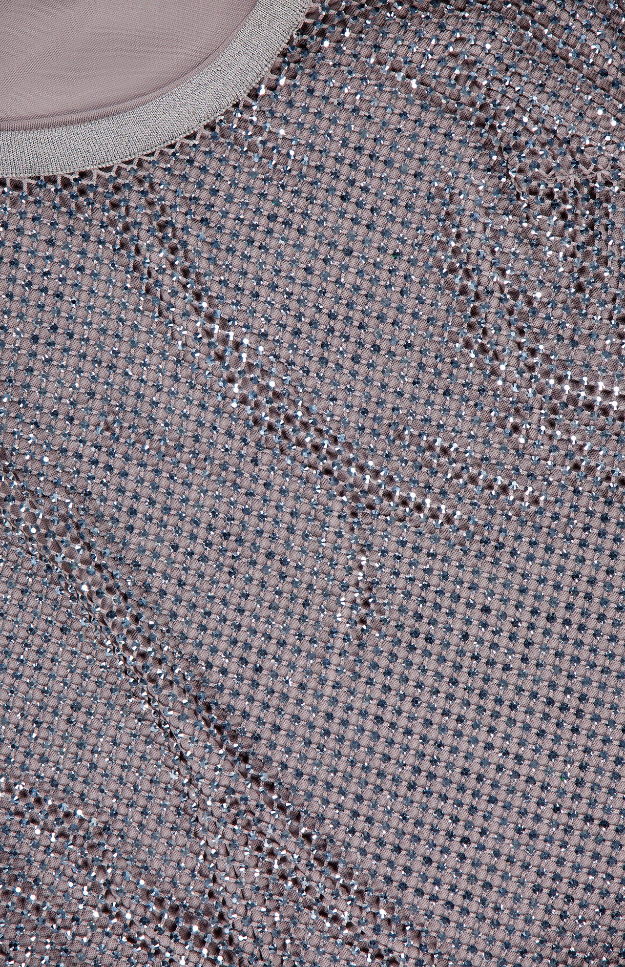 Close-up of the Melony Sleeveless Blouse by RALPH LAUREN COLLECTION, featuring textured rhinestone mesh with small, shiny silver dots on light brown fabric and a curved seam with a solid border in the top left corner.