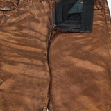 Close-up of the Mercer Cotton Denim Full Length Wide Pant by RALPH LAUREN COLLECTION, shown in metallic bronze with a shiny, textured finish, partially unzipped fly, black interior lining, waistband label, and visible front pocket stitching.