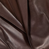 Close-up of the Parker Leather Slim Fit Blazer by RALPH LAUREN COLLECTION, showcasing its smooth chocolate brown leather, precise stitching, smart pocket design, and a single glossy black button.