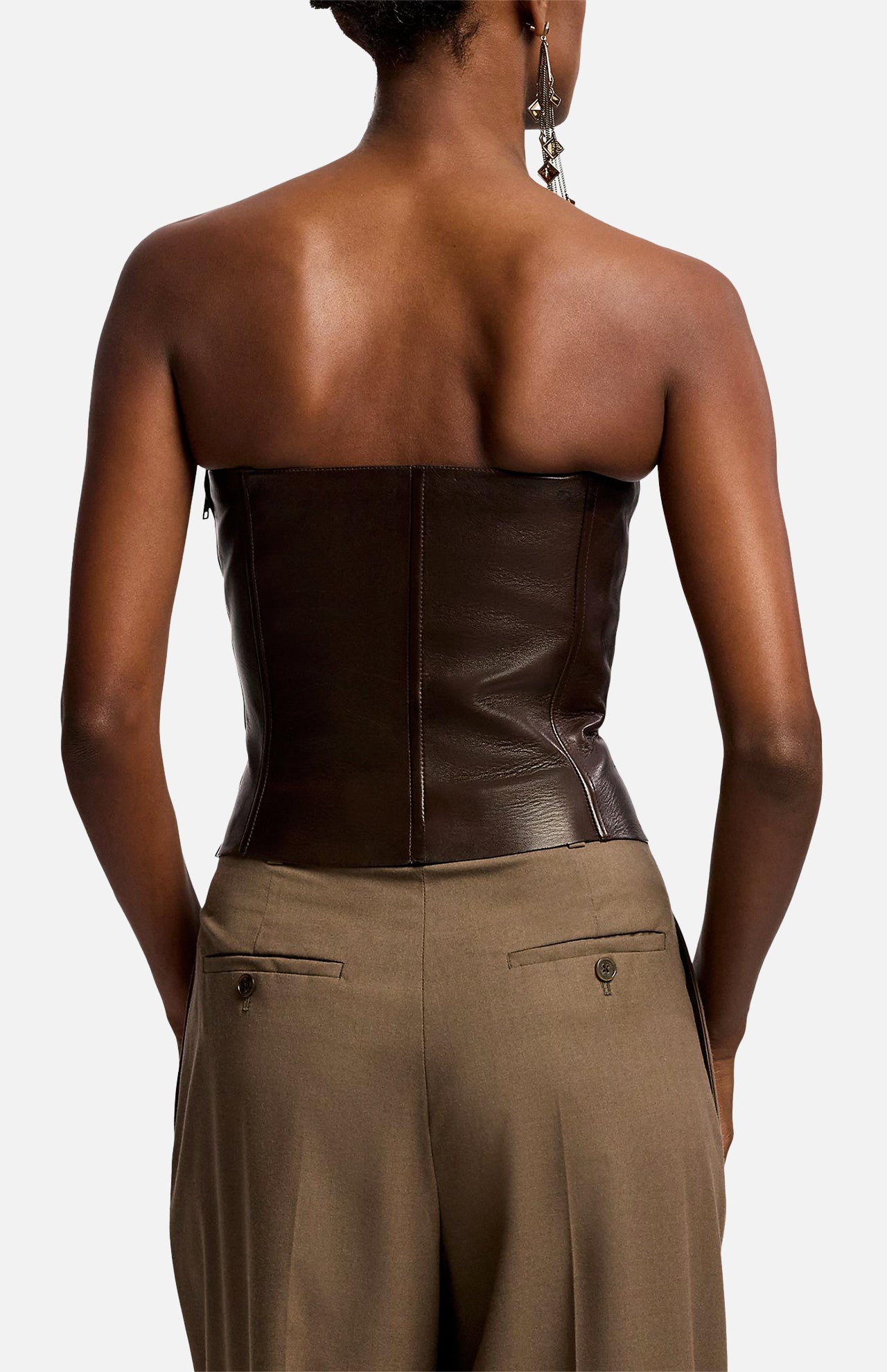 A person viewed from behind, wearing a dark brown Ralph Lauren Collection Plonge Leather Strapless Bandeau Top and tan trousers.