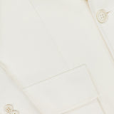 Close-up of the Preston Herringbone Tweed Blazer by RALPH LAUREN COLLECTION in white, showcasing its lapel, sleeve buttons, chest pocket, and refined fabric texture.