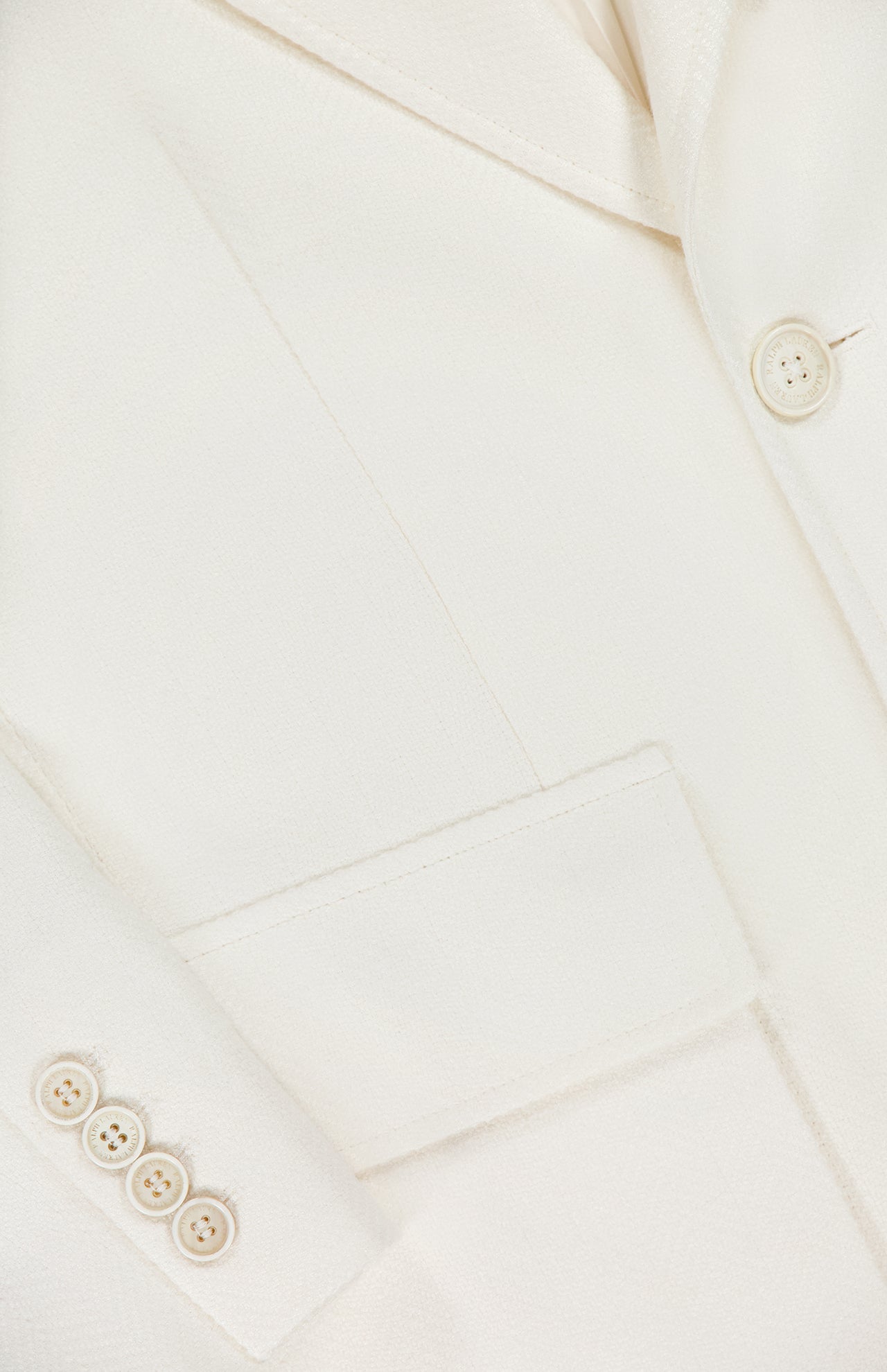 Close-up of the Preston Herringbone Tweed Blazer by RALPH LAUREN COLLECTION in white, showcasing its lapel, sleeve buttons, chest pocket, and refined fabric texture.