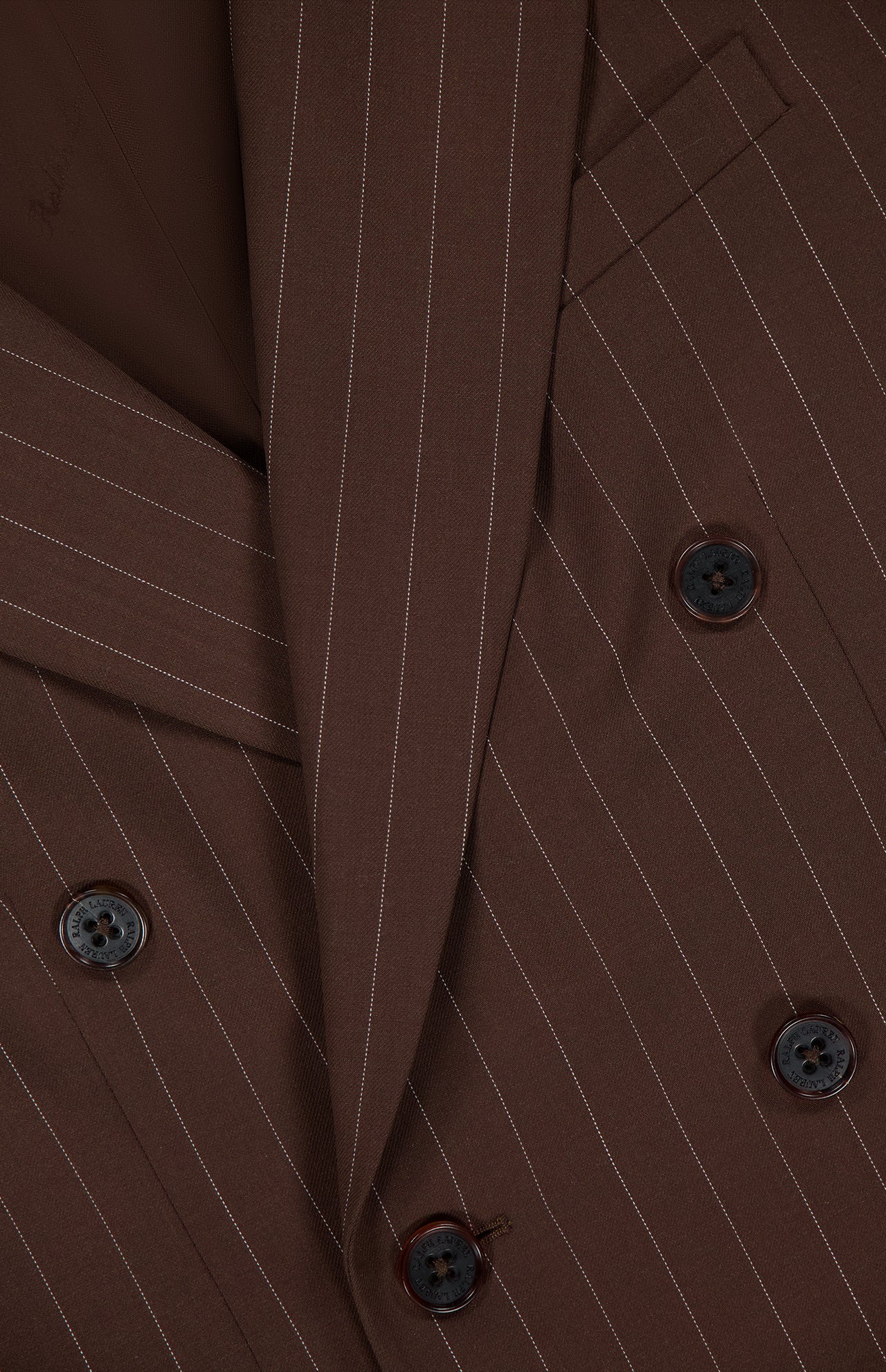 Close-up of the Ramona Wide Stripe Blazer by RALPH LAUREN COLLECTION, featuring dark brown wool with white pinstripes, dark buttons, a notched lapel, and a smooth tailored finish that emphasizes its double-breasted classic style.