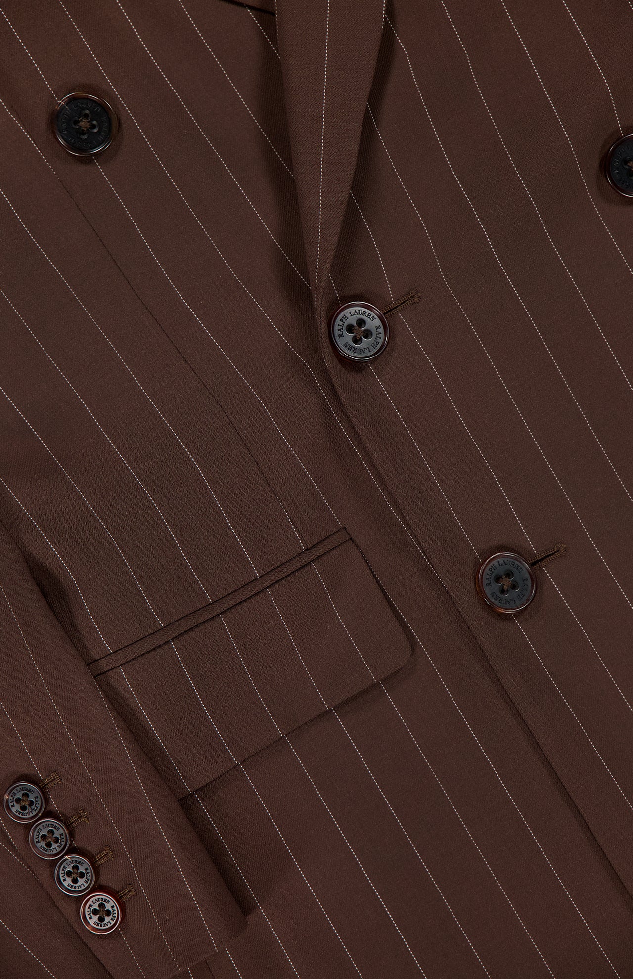 Close-up of the Ramona Wide Stripe Blazer by RALPH LAUREN COLLECTION, featuring dark brown wool with white pinstripes, a double-breasted front, detailed sleeve buttons, and a front pocket for an elegant, refined look.