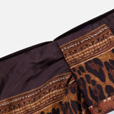 Close-up of the Scenic Silk Twill Pencil Skirt by RALPH LAUREN COLLECTION, featuring a brown and black leopard print, ornate gold decorative trim, and dark brown silk twill fabric. The image highlights a folded seam detail against a plain white background—showcasing the luxurious Italian craftsmanship of this designer skirt.
