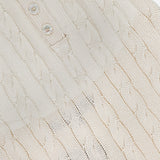 Close-up of the RALPH LAUREN COLLECTION Sleeveless Halter Polo Pullover Sweater, featuring a cream-colored cableknit texture and four pearl-like buttons on the collar—a stylish, breathable option for summer layering.