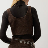 A woman wears a brown Tweed Scoop Neck Vest Top over a dark brown turtleneck sweater with a matching tweed skirt and a dangling charm chain belt.