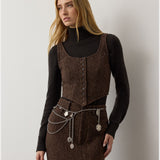 A woman with long blonde hair wears the RALPH LAUREN COLLECTION Tweed Scoop Neck Vest Top in dark brown wool cashmere blend, paired with a matching skirt, a black turtleneck, and a layered silver chain belt with pendants, standing against a plain light background.