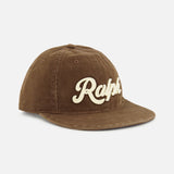 A cotton twill baseball cap from RALPH LAUREN POLO, featuring a curved brim and “Ralph” embroidered in large cream-colored script across the front, classic logo embroidery details, and an adjustable leather strap at the back.