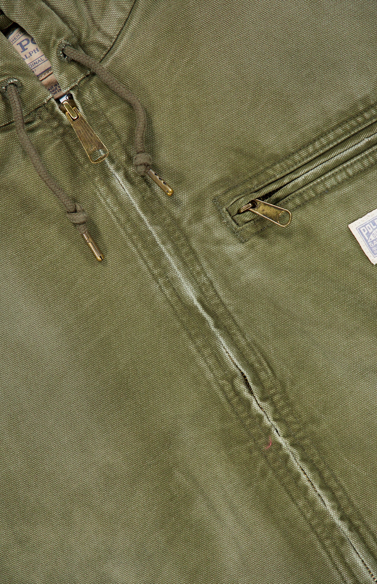 Close-up of the RALPH LAUREN POLO Denim Full-Zip Sherpa Long Sleeve Jacket in a grey-green wash, featuring sturdy metal zippers, adjustable drawstrings, and a small fabric tag on the pocket. The fabric shows gentle wear along the zipper seam, enhancing its subtle vintage denim appeal.