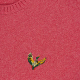A close-up of the pink Ducks Fly Crewneck Sweater by RALPH LAUREN POLO, featuring a colorful embroidered bird logo and part of the blue and yellow brand tag visible at the neckline.