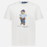 The Jersey Knit Novelty Denim Bear T-Shirt by RALPH LAUREN POLO is a classic-fit white cotton tee featuring a bear in a blue cap, jacket, jeans, and boots, with “Polo Bear by Ralph Lauren” and the designer's signature below.