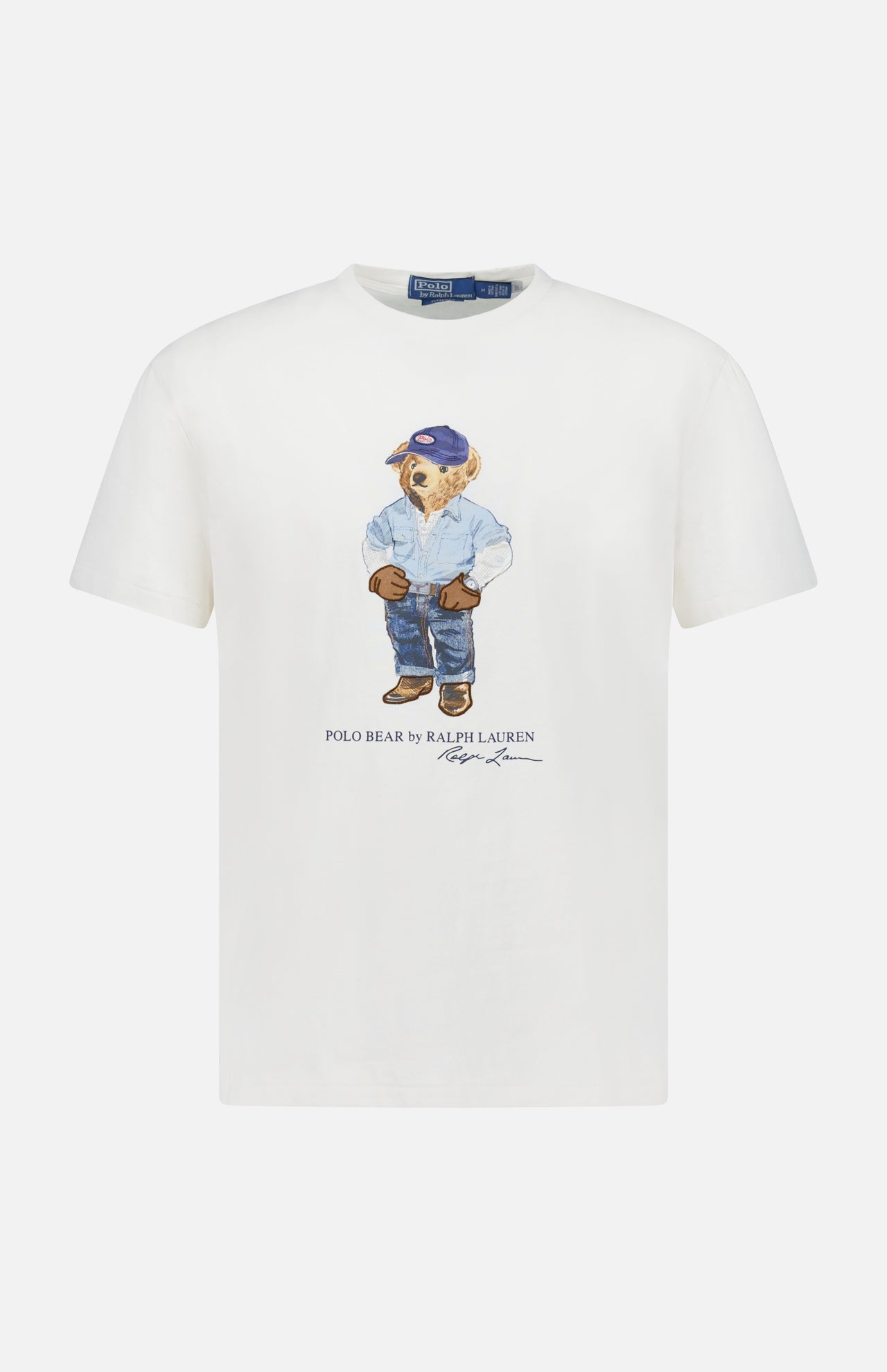 The Jersey Knit Novelty Denim Bear T-Shirt by RALPH LAUREN POLO is a classic-fit white cotton tee featuring a bear in a blue cap, jacket, jeans, and boots, with “Polo Bear by Ralph Lauren” and the designer's signature below.