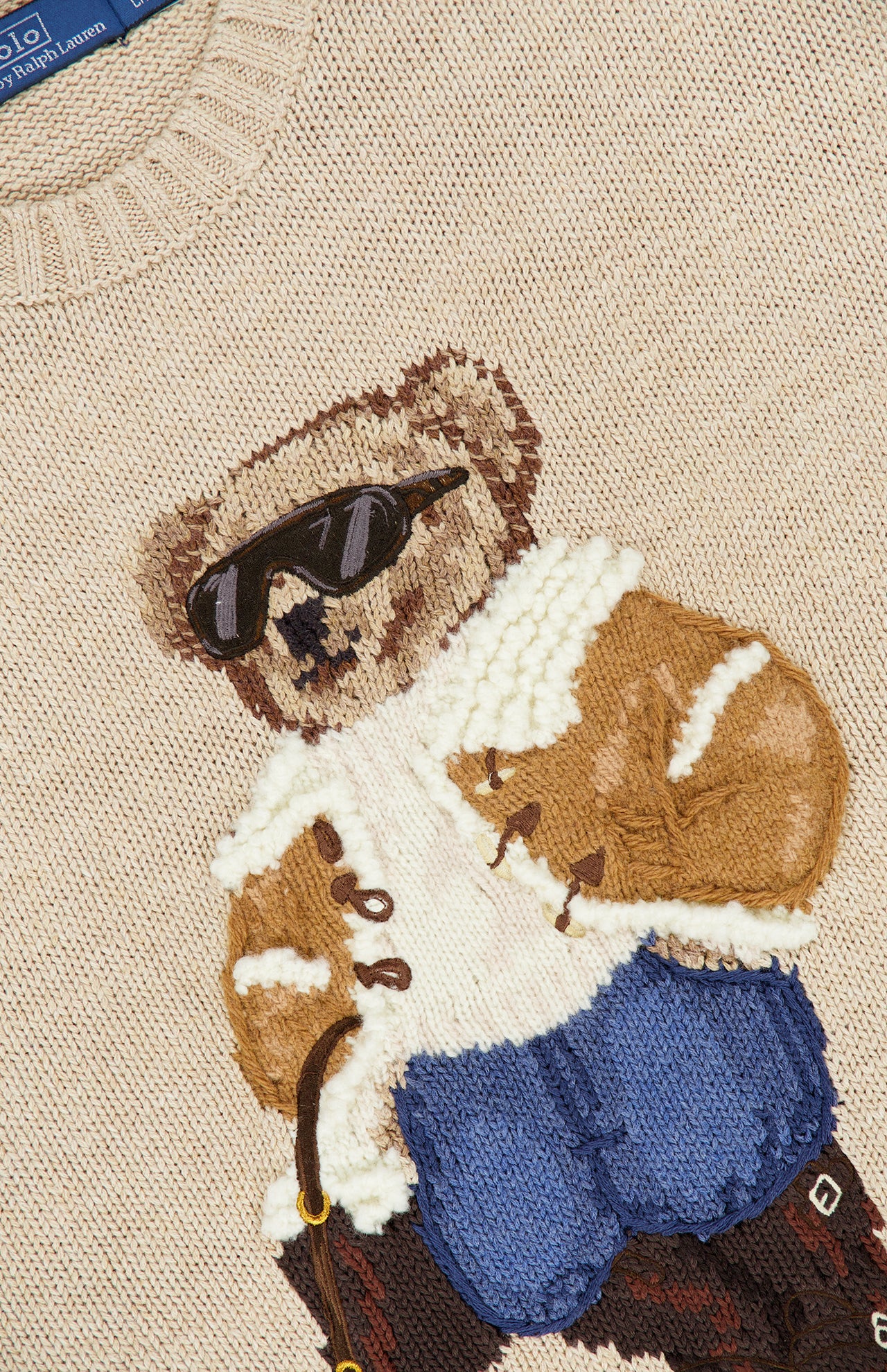 Beige Cotton Crewneck Polo Bear Sweater featuring a textured knit graphic of a bear wearing sunglasses, a shearling-lined jacket, and blue pants.